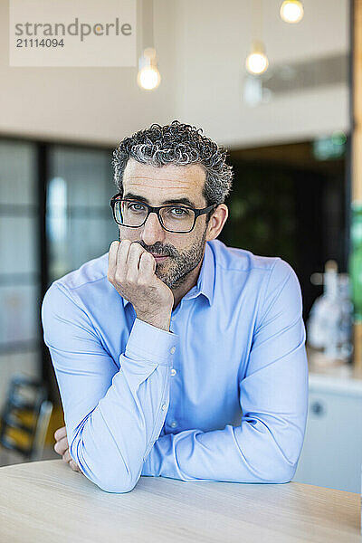 Contemplative businessman leaning on desk at co working space