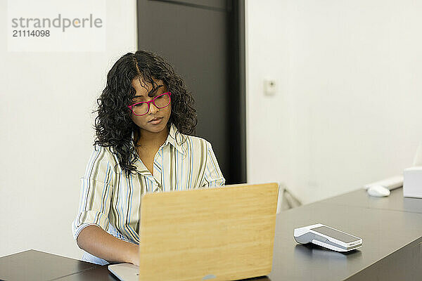 Business owner siting near table and using laptop at checkout