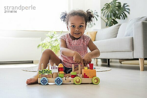 Smiling girl playing with toy vehicle at home