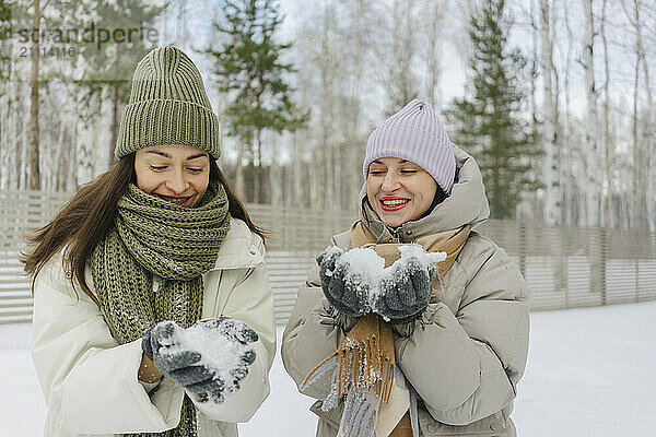 Happy friends playing with snow in winter