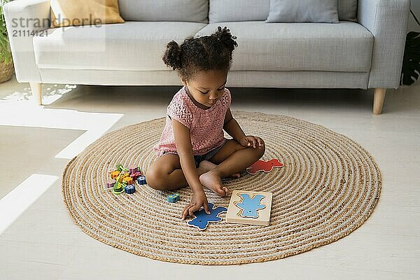 Girl sitting on rug and solving puzzles at home