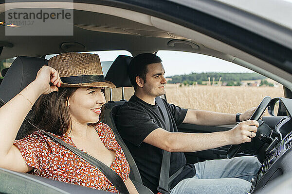 Smiling woman with boyfriend sitting near car window during road trip