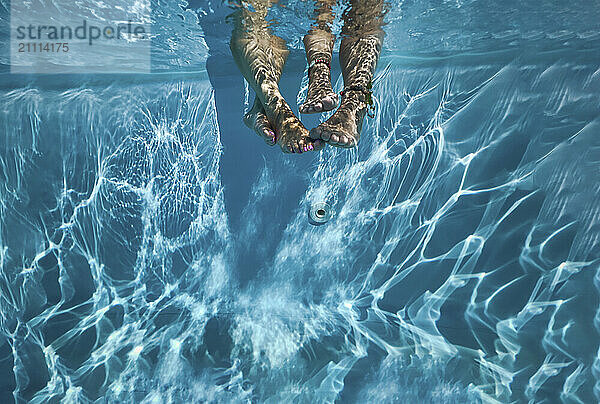 Feet of friends under water in swimming pool