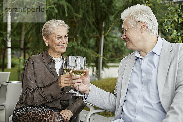 Happy couple toasting with white wine at outdoor restaurant