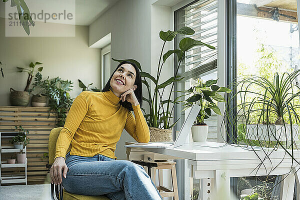 Happy woman leaning on elbow and day dreaming at home