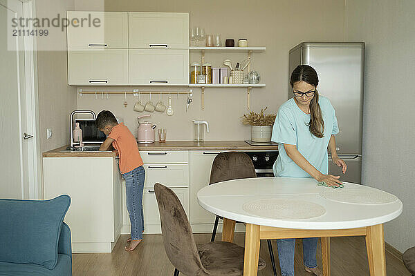 Son assisting mother in cleaning kitchen at home