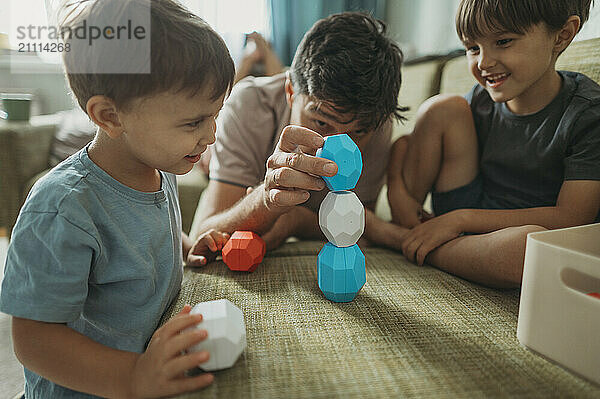 Mature man building toy blocks with children at home