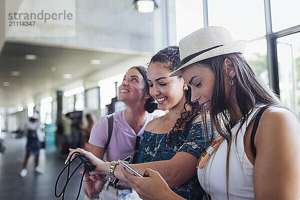 Woman using smart phone and waiting with friends at railroad station