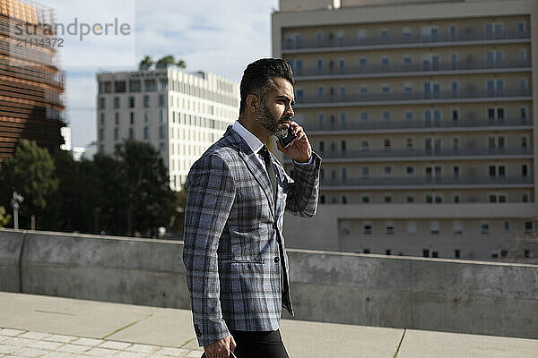 Businessman talking on smart phone outside building