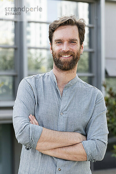 Confident businessman with arms crossed standing outside office