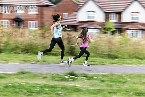 Determined mother and daughter sprinting on road