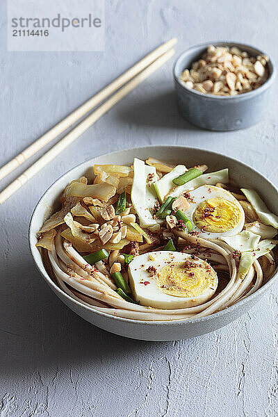 White cabbage soup with miso and udon noodles and boiled eggs and peanuts as topping