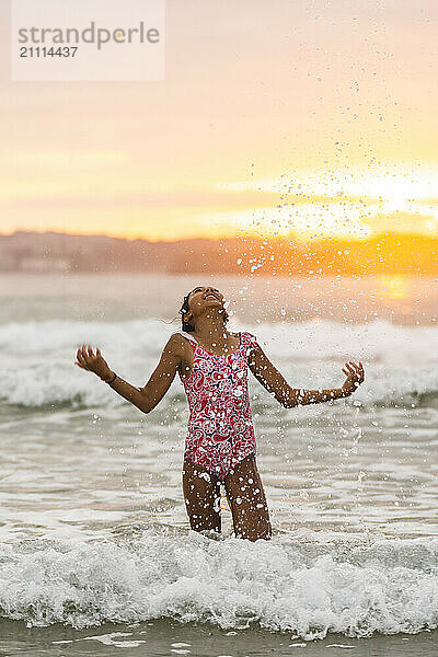 Carefree girl playing with water at beach