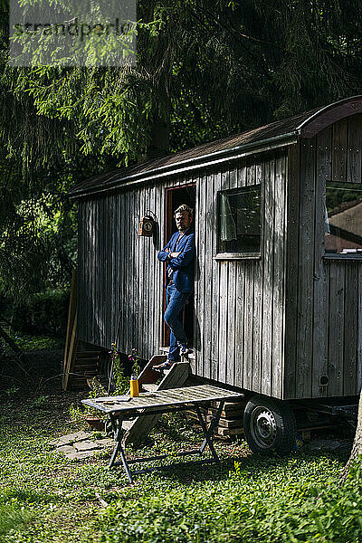 Businessman standing with arms crossed at doorway of log cabin