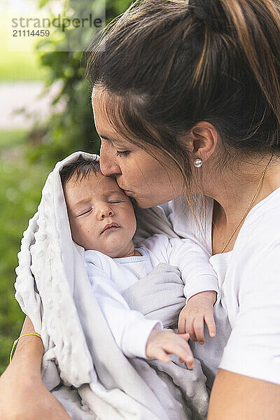 Affectionate mother kissing sleeping baby boy