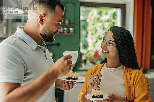 Couple eating slice of cake and drinking tea at home