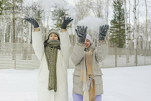 Happy friends throwing snow in winter