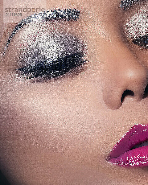 Close-up of a woman with dramatic silver eye makeup and pink lipstick showcasing a bold beauty look.