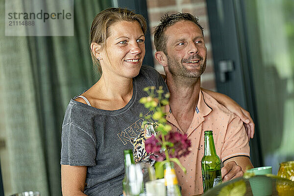 Smiling couple enjoying a casual outdoor gathering with drinks and food on the table.