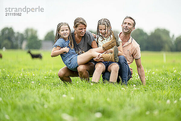 Family enjoying time together outdoors on green grass with smiles and affectionate poses.