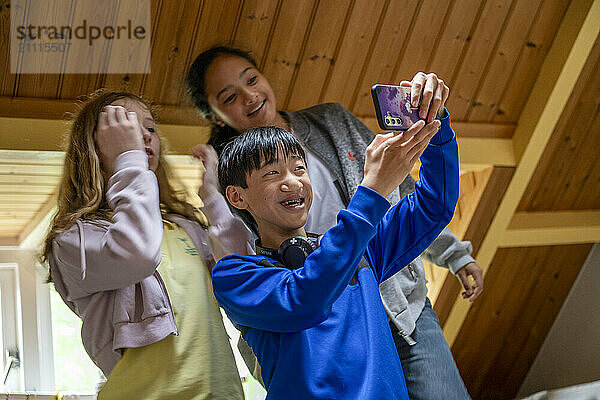 Three friends taking a selfie together indoors with a smartphone  smiling and enjoying their time.