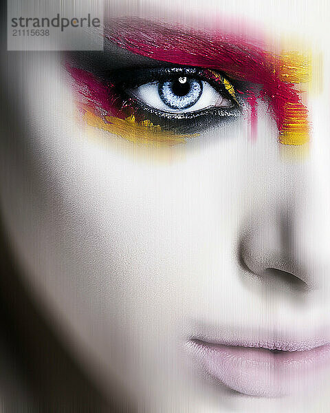 Close-up of a person's face with striking colorful makeup emphasizing one eye.