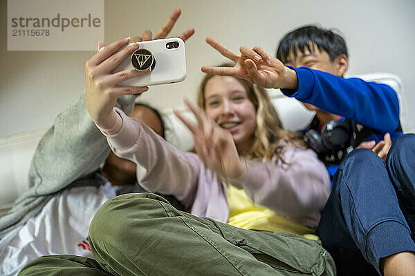 Smiling kids taking a selfie together with one making a peace sign.