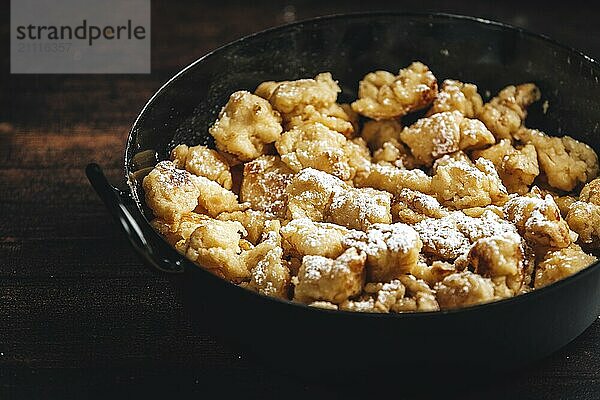 Nahaufnahme von Kaiserschmarrn in einer Pfanne mit Zucker bestreut  dunkler Hintergrund