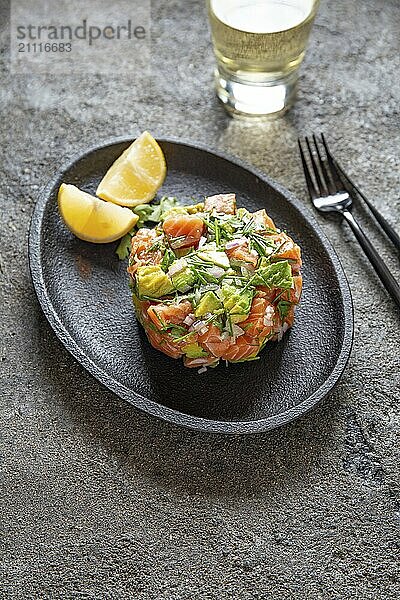 PERUANISCHEN NIKKEI ESSEN. Lachs Avocado Ceviche auf schwarzem Teller  schwarzer Hintergrund von oben