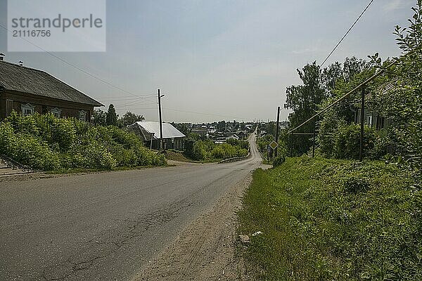 Dorfstraße  kleine Holzbrücke und einige Häuschen an einem sonnigen Sommertag