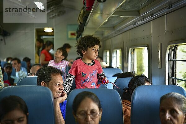 Ein Mädchen und ihr Vater im Zug  der aus dem Fenster schaut  in Indien