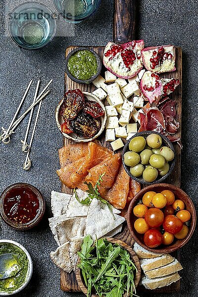 Antipasto. Wein Set Vorspeise. Schinken Serrano  geräucherter Lachs  getrocknete und frische Tomaten  Olivenkäse  Wein an Bord. Ansicht von oben  grauer Hintergrund aus Beton