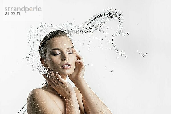 Schöne Frau mit geschlossenen Augen genießt den Wasserstrahl und die Spritzer von der Seite