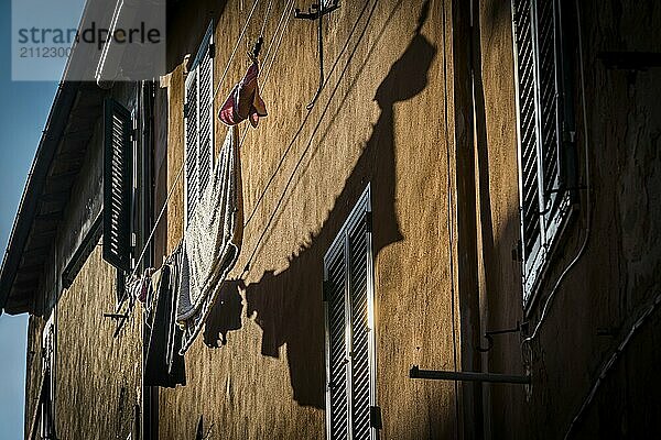 Hausfassade mit Wäscheleine in der Nachmittagssonne  Altstadt  Stimmungsvoll  Gegenlicht  Sonne  Abendsonne  dörflich  Dorf  Italien  Europa