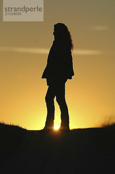 Silhouettenbild  Frau mit Jacke im Sonnenuntergang