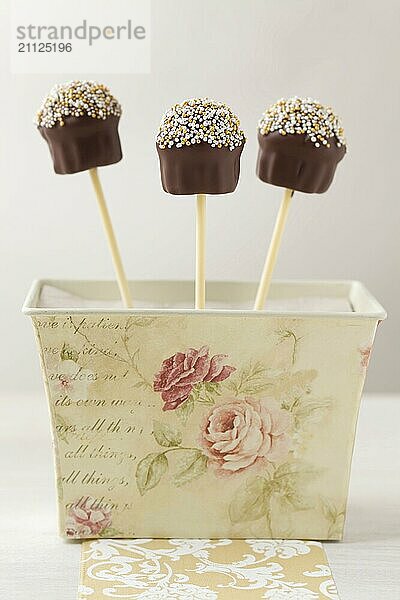 Cupcake förmige Cake Pops mit Schokolade und kleinen Perlen als Topping. Sie stecken in einer Vintage Geschenkbox. Sehr geringe Tiefenschärfe