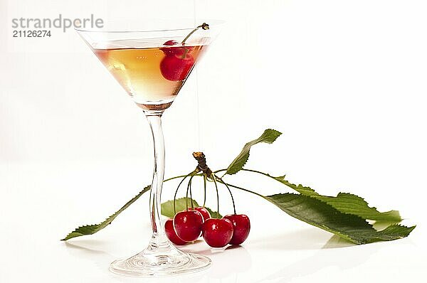 Frische Kirschen mit Cocktailglas vor weißem Hintergrund