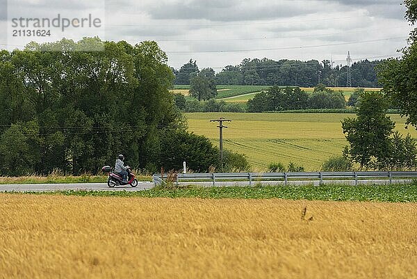 Mann fährt mit einem Motorroller auf der Straße durch die landwirtschaftlichen Felder  in der Nähe der Stadt Schwäbisch Hall  Deutschland  Europa