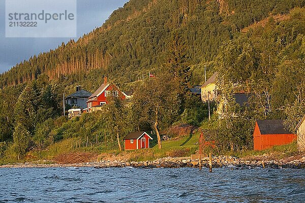 Mehrere Häuser in dem typischen Rot Norwegens am Ufer des Romsdalsfjord vom Wasser aus fofotgrafiert