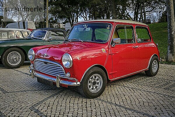 Lissabon  Portugal  20. Januar 2024: Ein klassischer roter Mark I Mini oder Austin Mini Super Deluxe mit verchromten Details ist auf einem Kopfsteinpflasterweg in der Nähe eines grünen Parks geparkt  Europa