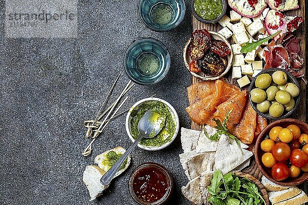 Antipasto. Wein Set Vorspeise. Schinken Serrano  geräucherter Lachs  getrocknete und frische Tomaten  Olivenkäse  Wein an Bord. Ansicht von oben  grauer Hintergrund aus Beton