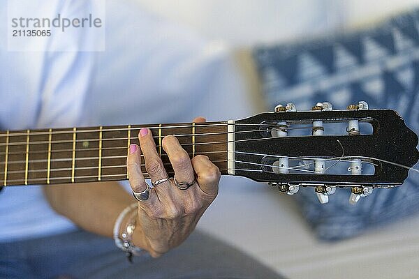 Nahaufnahme der Hände einer Gitarre spielenden Frau