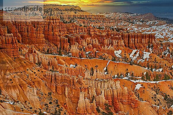 Weite Sicht auf einen Canyon mit orangefarbenen Felsen und schneebedeckten Hängen im Sonnenaufgang  Bryce Canyon  Utah  Amerika