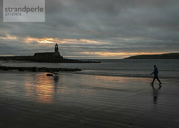 Silhouette des Harbour Light Tower und Spaziergänger in der Abenddämmerung  Port Logan  Dumfries & Galloway  Schottland  Großbritannien  Europa