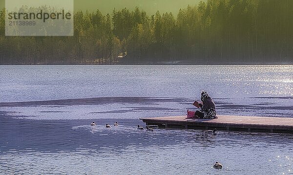 Slowenische junge Frau liest ein Buch und entspannt sich in der Natur auf einem Holzsteg am Bleder See  Slowenien  Europa