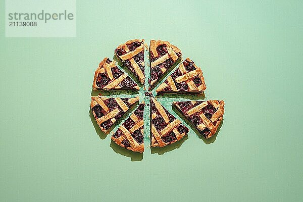 Blaubeerkuchen mit Gitterkruste auf grünem Hintergrund  Ansicht von oben. Hausgemachter Kuchen mit Blaubeerfüllung. Obstkuchen in 8 Portionen geschnitten