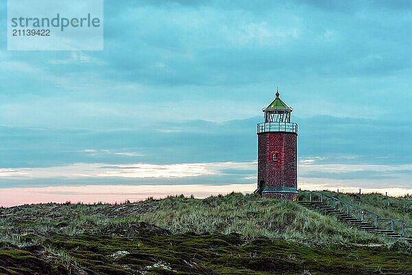 Abendlandschaft auf der Insel Sylt mit Hügeln aus Strandhafer  einem Leuchtturm aus roten Ziegeln und bewölktem Himmel. Schöne Landschaft auf der deutschen Insel Sylt in der Nordsee