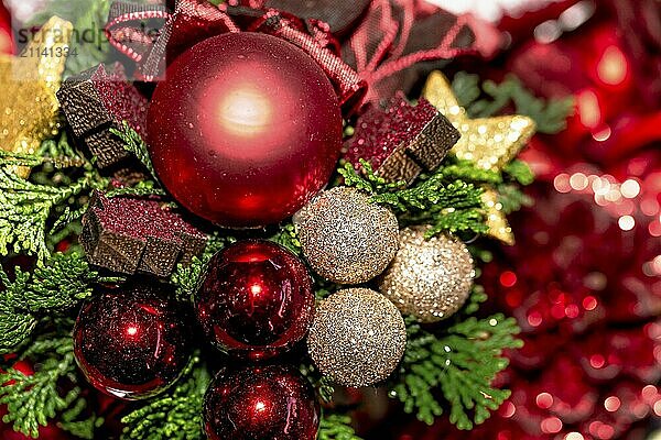 Weihnachtsdekoration mit roten und goldenen Weihnachstkugeln und grüner Tanne mit rötlichem Bokeh im Hinetrgrund