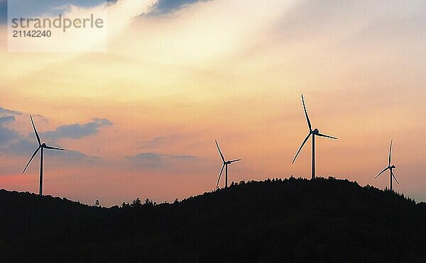 Silhouette von Windkraftanlagen  Stromgeneratoren  auf einem bewaldeten Hügel  bei Sonnenaufgang  in Baden-Württemberg  in der Nähe von Schwäbisch Hall  Deutschland  Europa