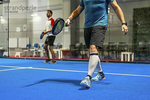 Zwei männliche  reife Freunde spielen Paddle Tennis in einer Halle